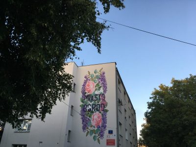 Widok na fasadę budynku i mural z napisem Miasto Ogród