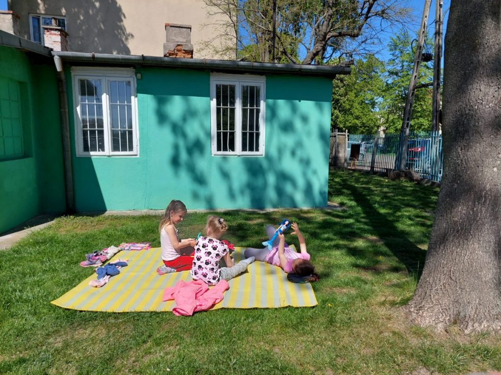 grupa wsparcia we Włochach dla dzieci ukraińskich uchodźców - dzieci siedzące na kocach na trawie